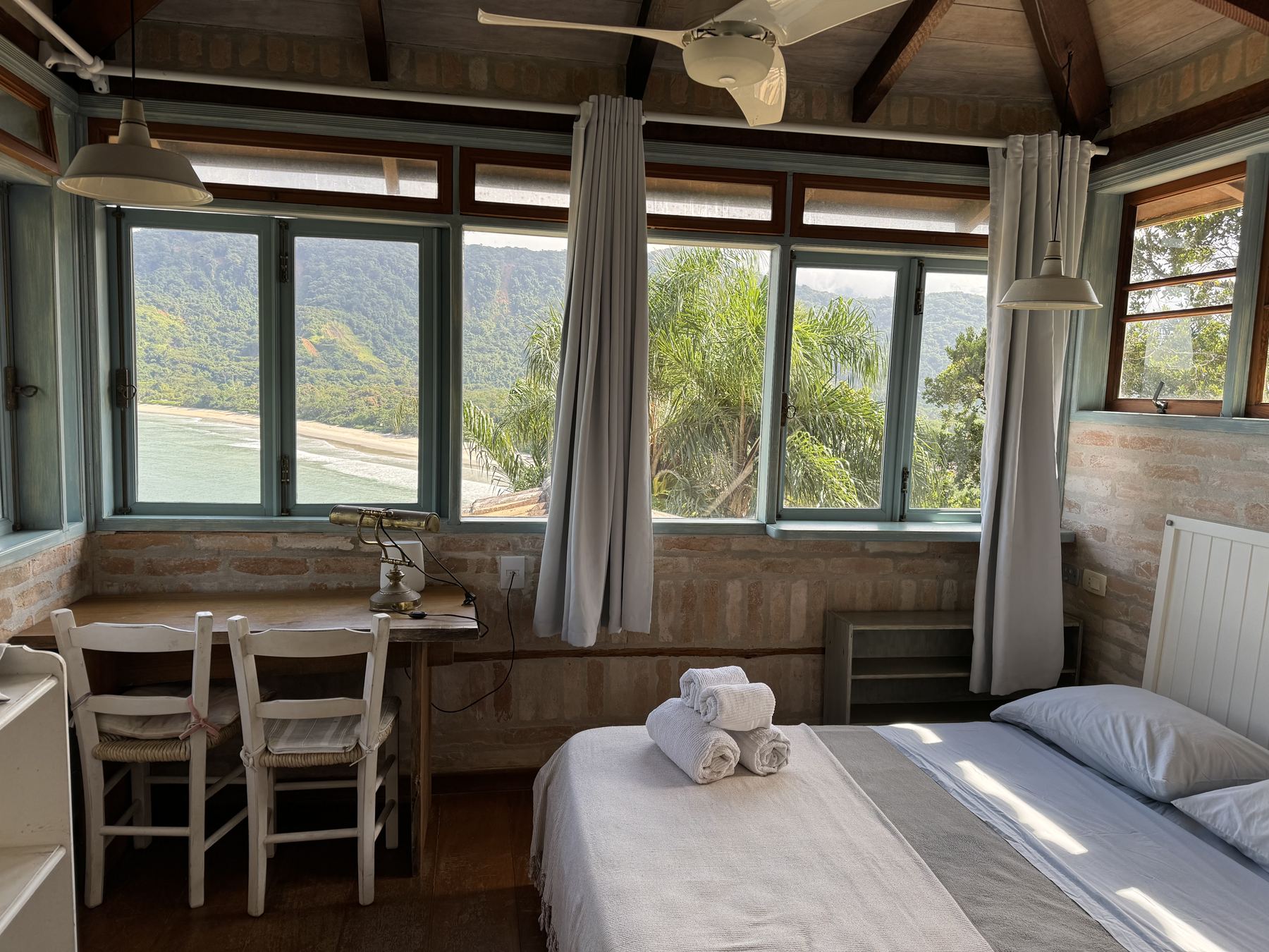 Chalé interior with bed, dining nook and view windows